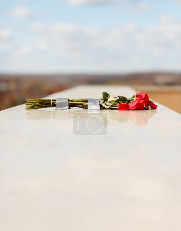 Téléchargez les photos : Bouquet de roses rouges placé sur le mur de marbre de pierre au tombeau commémoratif du mausolée - en image libre de droit