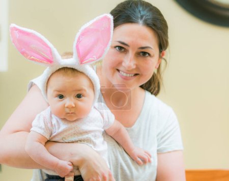 Foto de Bebé con orejas de conejo en brazos de madre en vacaciones de Pascua - Imagen libre de derechos