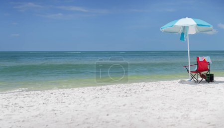 Foto de Relajación junto a la playa: silla, paraguas, nevera y toalla junto al océano - Imagen libre de derechos