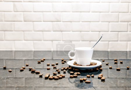 Foto de Taza de café expreso y cuchara con granos de café tostados oscuros con mostrador moderno y azulejo del metro blanco en la cocina bar cafetería - Imagen libre de derechos