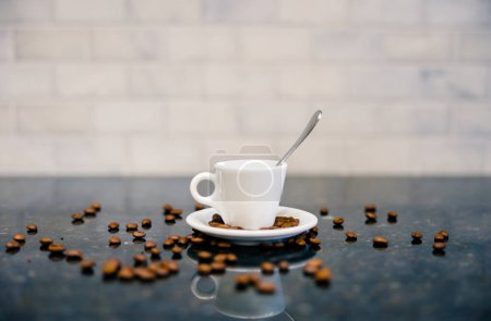 Foto de Taza de café expreso y platillo con cuchara y granos de café tostados oscuros con mostrador moderno y azulejo del metro blanco en la cocina bar cafetería - Imagen libre de derechos