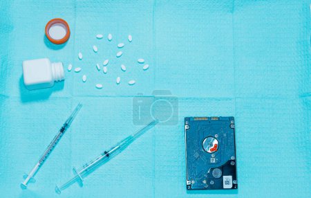 Foto de Vista aérea de una bandeja médica que contiene agujas hipodérmicas, pastillas y un frasco de pastillas, y una unidad de disco duro - Imagen libre de derechos