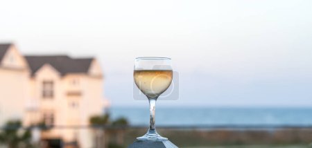 Téléchargez les photos : Verre à vin avec océan en arrière-plan au coucher du soleil - en image libre de droit