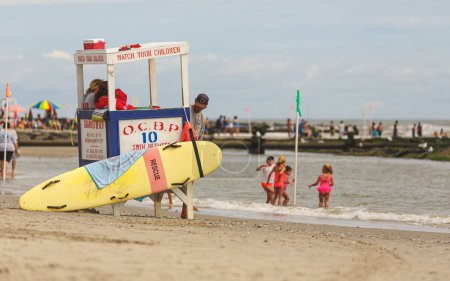 Foto de Ocean City New Jersey Torre de salvavidas en la playa con tabla de rescate de surf con niños nadando jugando en el fondo - Imagen libre de derechos