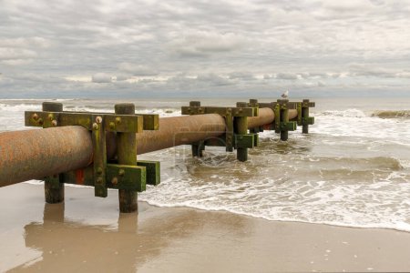 Téléchargez les photos : Pompe à eau industrielle se jetant dans l'océan au bord de la plage - en image libre de droit