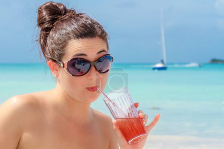 Téléchargez les photos : Jeune femme sirotant un verre au paradis de la plage tropicale - en image libre de droit