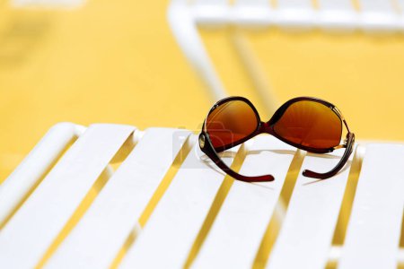 Téléchargez les photos : Lunettes de soleil sur chaise longue piscine avec fond jaune - en image libre de droit