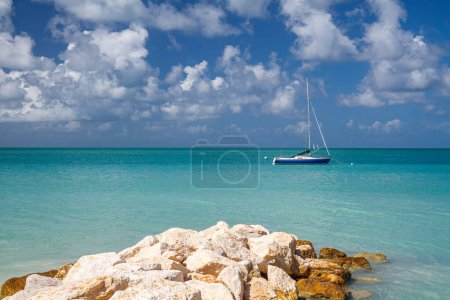 Foto de Antigua Barbuda playa con muelle de roca y fondo paisaje velero - Imagen libre de derechos