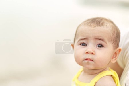 Photo for Infant baby portrait with bright eyes eyelashes isolated with shallow depth of field against light colored background - Royalty Free Image