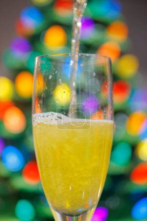 Festive Champagne Glass Toast with Colorful Christmas Bokeh Ligh