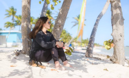 Téléchargez les photos : Beach Relaxation Femme jouissant de la sérénité sous le palmier sur Smathers Beach à Key West, Floride - en image libre de droit