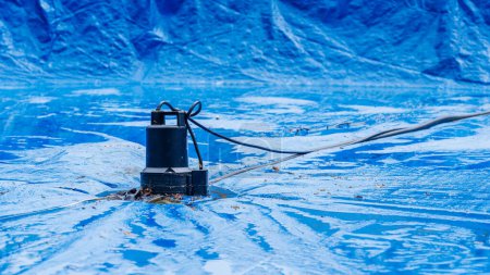 Téléchargez les photos : Piscine efficace hivernant avec pompe à eau sur la couverture de la piscine - en image libre de droit