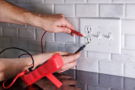 Electrician testing electrical outlet with multimeter