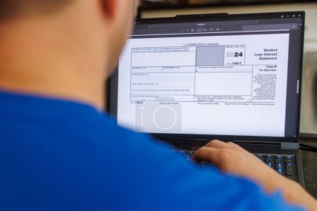 Person Student Filling out 1098-E Student Loan Interest Form Digital Online pdf version 2024 on laptop computer