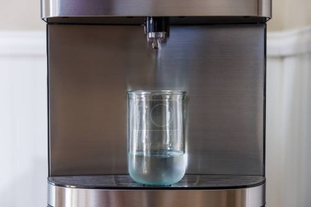 Foto de Vidrio de llenado del dispensador de agua con agua - Imagen libre de derechos