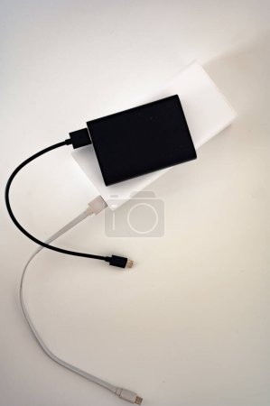 Photo for Black power bank on white mobile charger with white and black cord cable connected. White background. - Royalty Free Image