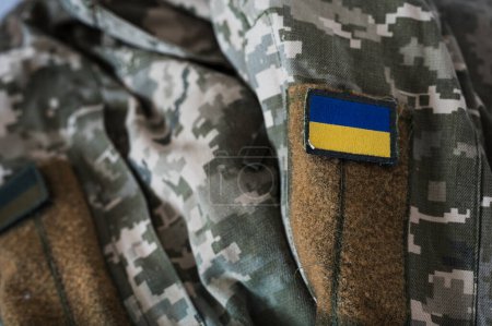 Un estandarte de la bandera ucraniana en un uniforme de camuflaje de píxeles de soldado. Traje de camuflaje militar digital pixelado con bandera ucraniana en chevron en colores azul y amarillo. Uniforme soldado ucraniano