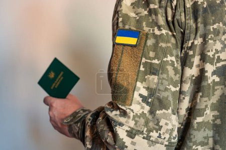 Soldat im Taktikanzug hält militärischen Ausweis in der Hand. Ukrainische Pixeluniform