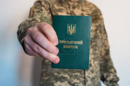 Photo for Soldier in camouflage holds military id doc in right hand. Ukrainian pixel - Royalty Free Image