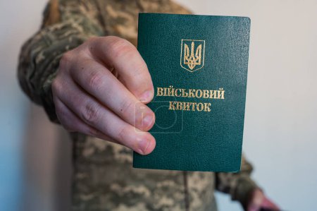 Soldier in camouflage holds military id doc in hand. Ukrainian pixel