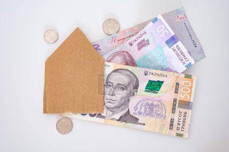 Monnaie ukrainienne, pièces de monnaie et maison de papier sur le fond blanc. Pour la finance, économie, logement, mortage, coût de la vie, Ukraine