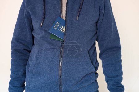 Photo for Civil man with ukrainian passport and green document sticking out from blue sweatshirt - Royalty Free Image