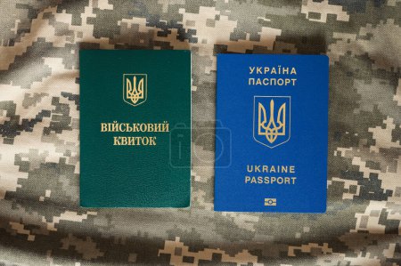Photo for Translation: "military id". Ukrainian passport and military doc on camouflage pixel background. Mobilization, travel, law - Royalty Free Image
