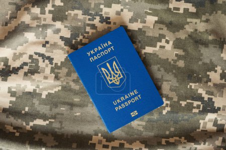 Pasaporte extranjero civil ucraniano sobre fondo de píxeles de camuflaje militar. Control fronterizo