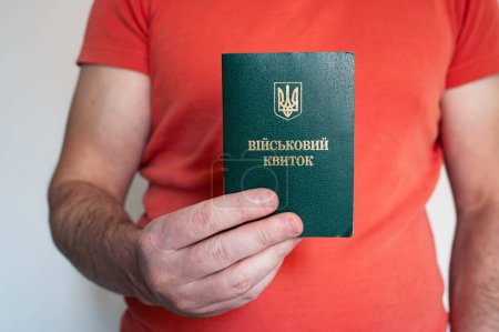 Translation: "military id". Civil man holds ukrainian military id. Soldier, mobilization, veteran, rookie, document