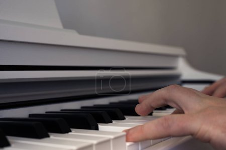 Photo for Mens hands playing on white upright piano. Musical theme. Piano keyboard - Royalty Free Image