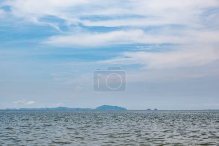 Photo for The sea with a slight breeze was the scenery, and far away, there were tall buildings and mountains in the middle of the sea. - Royalty Free Image
