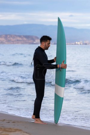 Téléchargez les photos : Surfeur en néoprène et planche de surf sur la plage - en image libre de droit