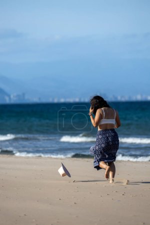 Girl running after her hat that is blown away by the wind