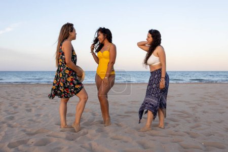 Drei multirassische Mädchen hängen am Strand herum