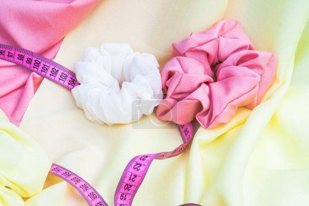 Téléchargez les photos : Trois scrunchies blanches, roses et jaunes sur tissu rose doux. Concept de coiffure - en image libre de droit