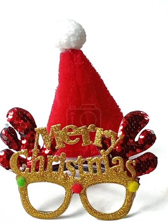 Téléchargez les photos : Lunettes fantaisie en bois d'or et chapeau de Père Noël pour les fêtes placées sur un fond blanc. Plan rapproché d'eux. - en image libre de droit