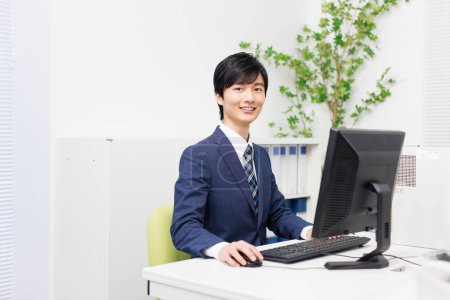 Schöner japanischer Geschäftsmann arbeitet im modernen Büro am Computer 