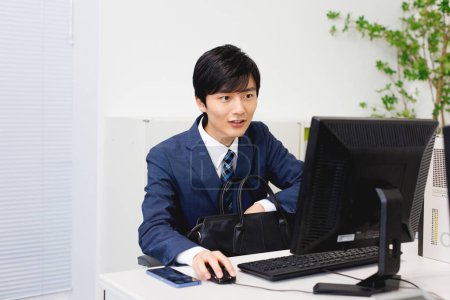 Schöner japanischer Geschäftsmann arbeitet im modernen Büro am Computer 