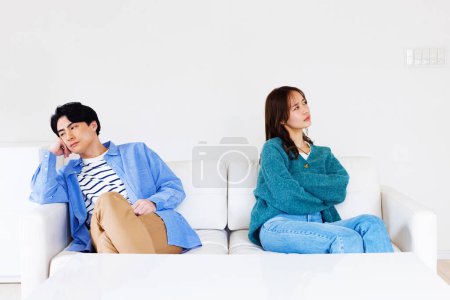Foto de Joven pareja japonesa sentado en sofá en casa y no hablar entre sí después de la discusión - Imagen libre de derechos