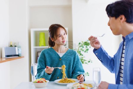 Téléchargez les photos : Jeune femme manger des nouilles avec son mari - en image libre de droit