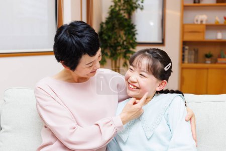 Téléchargez les photos : Asiatique mère et fille sur canapé à la maison - en image libre de droit