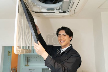Foto de Joven asiático hombre reparación aire acondicionado unidad en casa. - Imagen libre de derechos