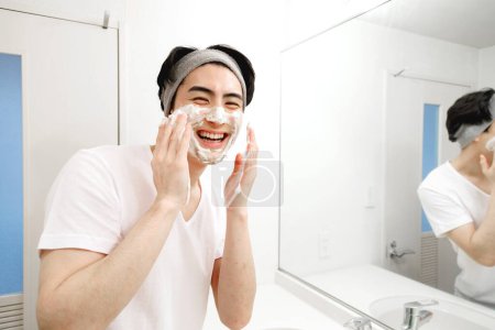 Téléchargez les photos : Portrait d'un beau jeune Japonais se lavant le visage pendant la routine matinale à la maison - en image libre de droit