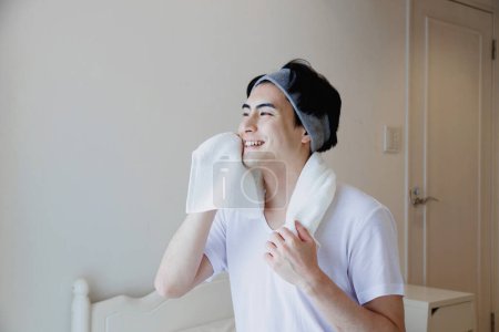 Téléchargez les photos : Portrait d'un beau jeune Japonais se lavant le visage pendant la routine matinale à la maison - en image libre de droit