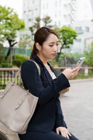 Photo for Portrait of beautiful japanese businesswoman in suit using mobile phone on the street - Royalty Free Image
