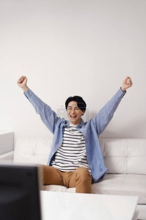 Photo for Happy young asian man celebrating success at home. - Royalty Free Image