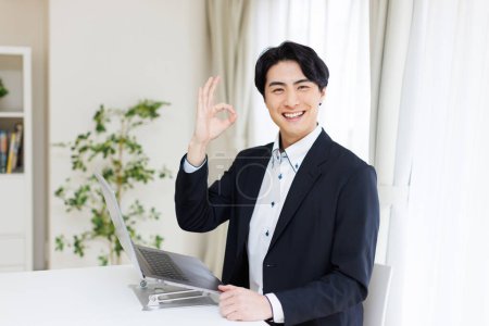 Téléchargez les photos : Homme d'affaires avec ordinateur portable montrant ok signe - en image libre de droit