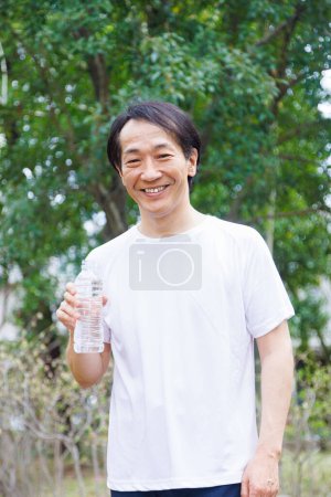 Photo for Asian man with bottle of water after jogging in the park. - Royalty Free Image