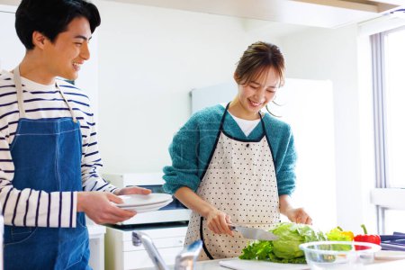 Photo for Couple preparing fresh vegetable salad in kitchen - Royalty Free Image