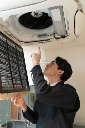 Foto de Joven asiático hombre reparación aire acondicionado unidad en casa. - Imagen libre de derechos